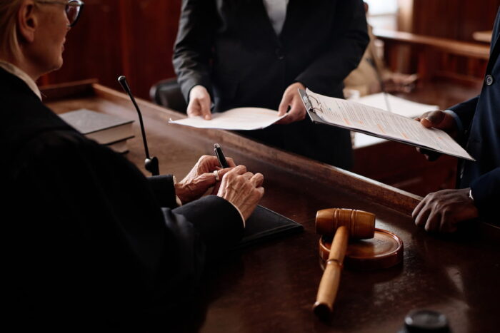 reasons to get a lawyer after a car accident – Legal professionals discussing paperwork in a courtroom setting, symbolizing the legal processes that may follow an accident.