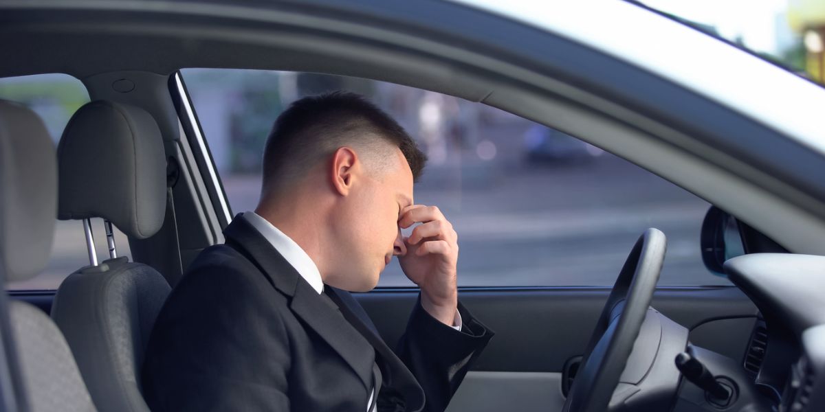 Exhausted male in formal suit sitting on driver seat after a rideshare accident