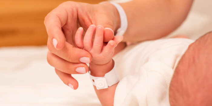 Parent holding a newborn’s hand in a hospital setting representing birth injury cases and concerns about medical negligence during delivery