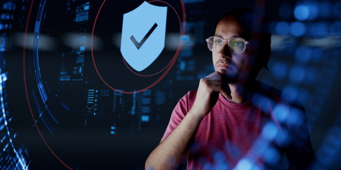 Person analyzing digital security data with a shield icon representing business fraud detection tools and cybersecurity monitoring