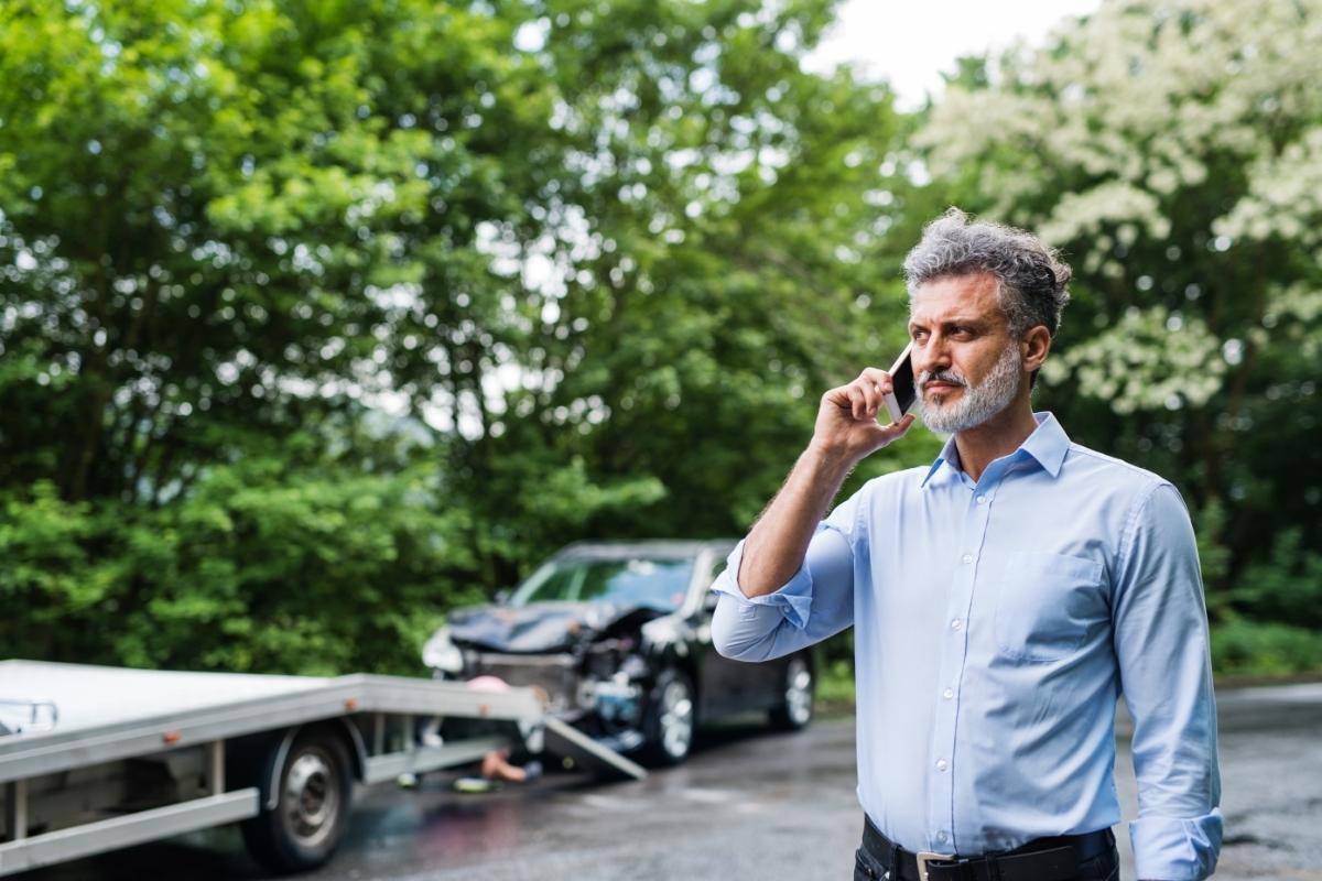 man on the phone waiting for his car to be picked up after t-bone accidents